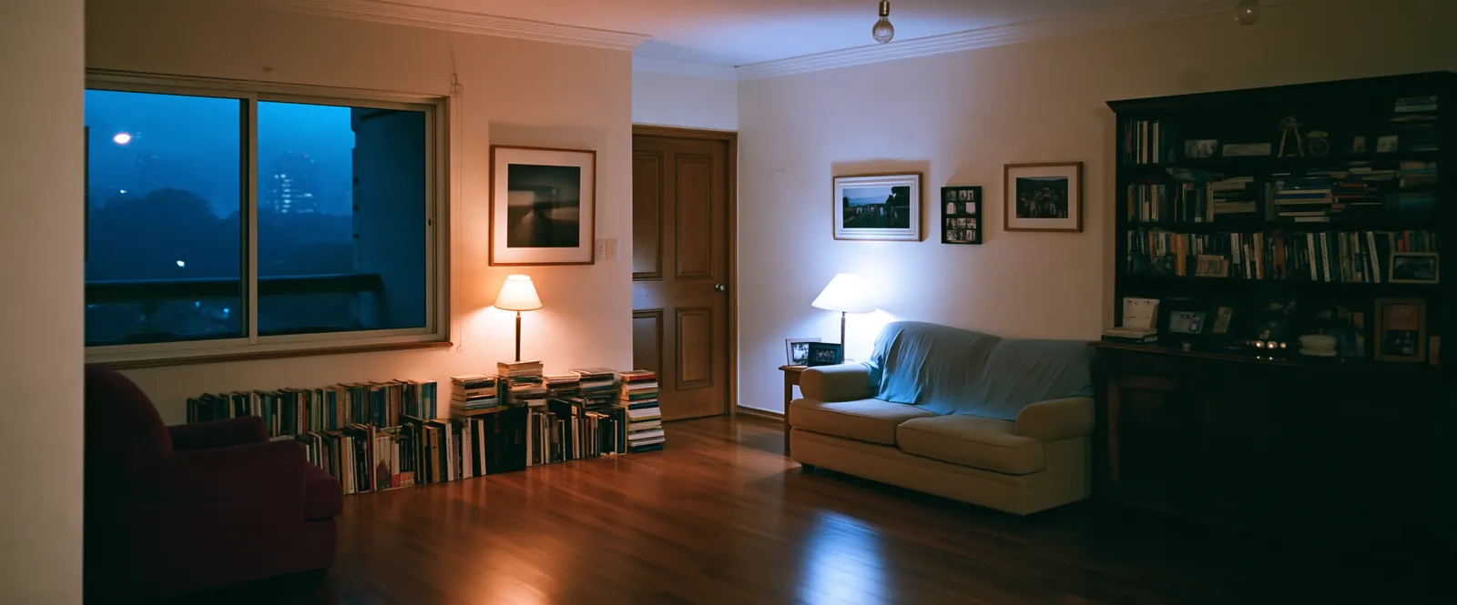 Location created with artificial intelligence by ZerezoFilms AI Studio: an apartment with bookshelves and lamps on at blue hour