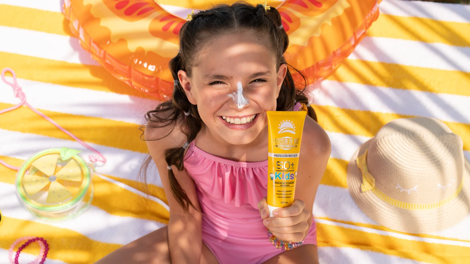 Fotografía de campaña Fotosun Kids por ZerezoFilms: niña con protector solar en toalla de playa